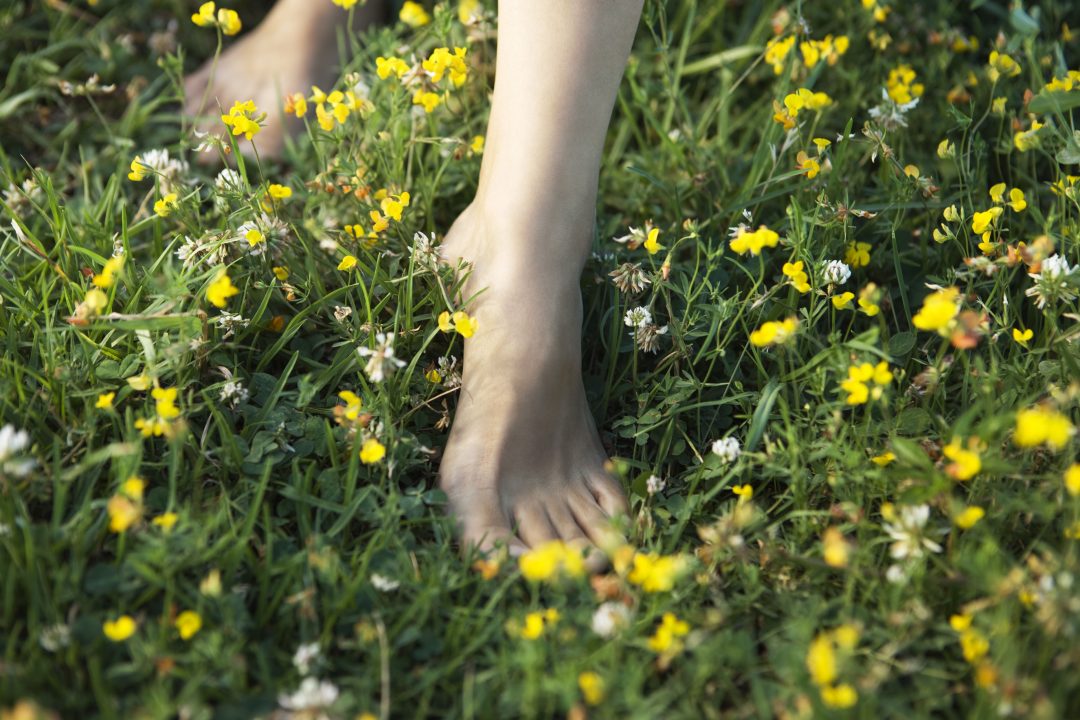 Femme marchant pieds nus dans un champ de fleurs sauvages, image recadrée | Woman walking barefoot in field of wildflowers, cropped